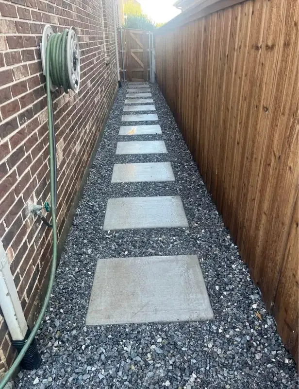 Finished stepping-stone path with dark aggregate beside a brick home