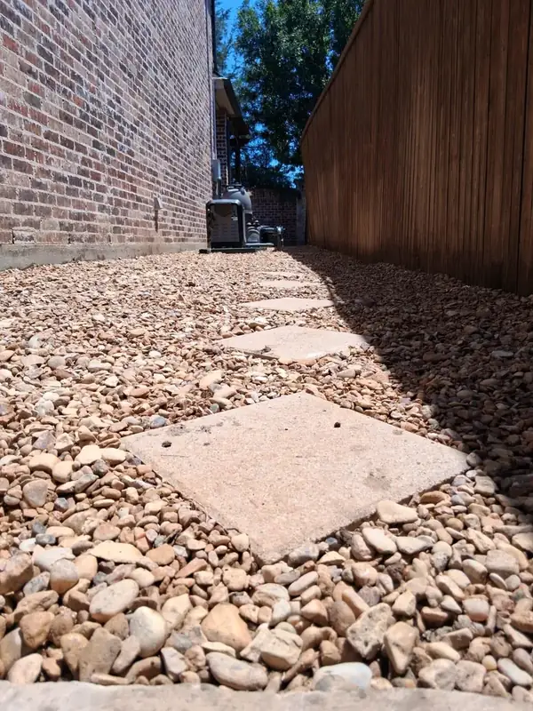 Square stepping stones within a gravel-finished residential side yard